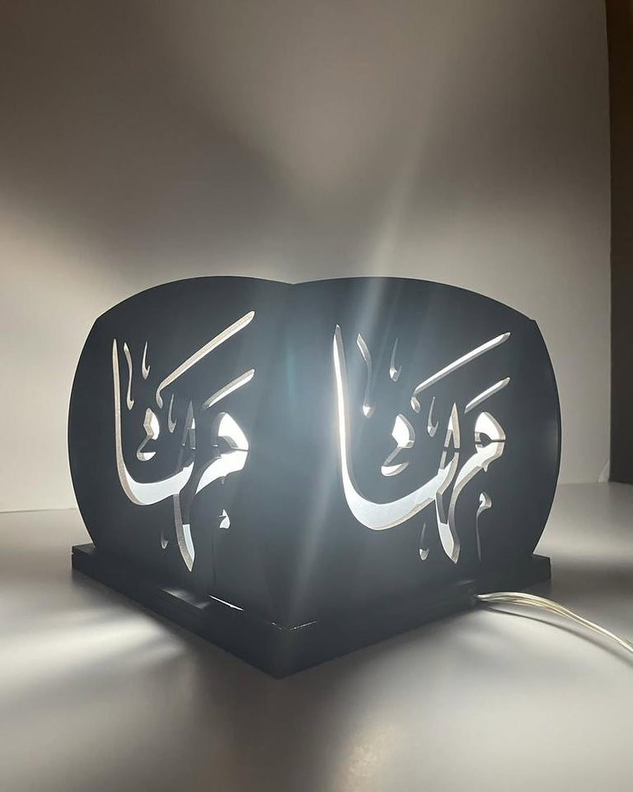 A Light box rendered in hand-cut Arabic calligraphy, backlit as a custom lamp.