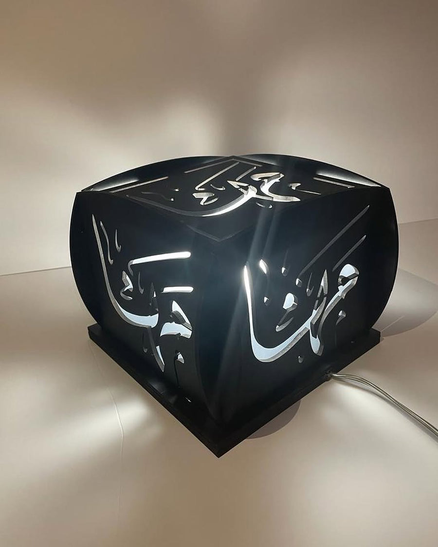A Light box rendered in hand-cut Arabic calligraphy, backlit as a custom lamp.